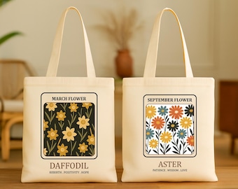 May include: Two canvas tote bags with floral designs. One features daffodils with the text "March Flower" and "Daffodil". The other displays asters with the text "September Flower" and "Aster". Both bags have cream-colored handles.