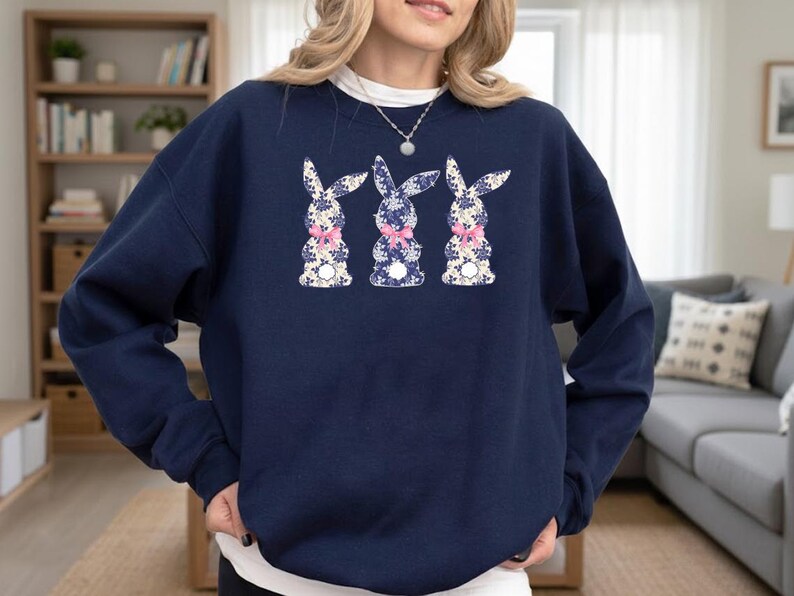 Puede incluir: Sudadera azul marino con tres conejos con estampados florales y lazos rosas. Los conejos est&aacute;n centrados en la parte delantera de la sudadera. Cuello redondo y mangas largas.