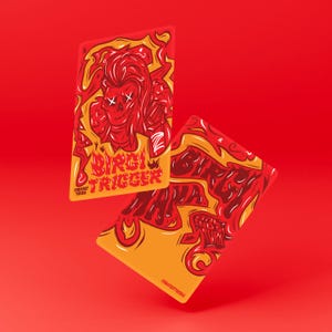 Puede incluir: Dos tarjetas coleccionables rectangulares con un diseño de llamas en rojo y naranja vibrante. Una tarjeta presenta un personaje de calavera con ojos en forma de X y el texto Birgi Trigger. La otra muestra el texto Birgi Mana en letra estilizada.