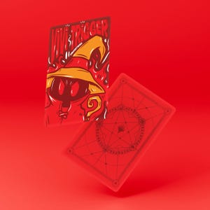 May include: Two red playing cards with a cartoon wizard illustration and the text "VIVE TRIGGER". The wizard wears a yellow hat and has a question mark. The back of the card has a circular design.