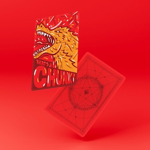 Puede incluir: Dos cartas rojas. Una carta presenta una ilustración de dragón con el texto "THAT'S A CHUNKY". La otra carta tiene un diseño geométrico rojo. Las cartas están sobre un fondo rojo.