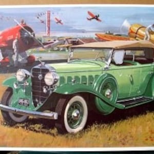 May include: A vintage green 1932 Cadillac convertible with a tan top, parked on a grassy field with several red and yellow airplanes in the background.