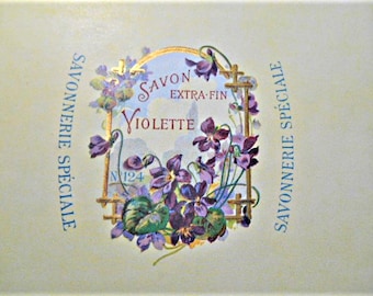 Puede incluir: Una etiqueta de jabón vintage con un marco dorado y flores violetas. El texto dice "Savon Extra Fin Violette" y "Savonnerie Spéciale".