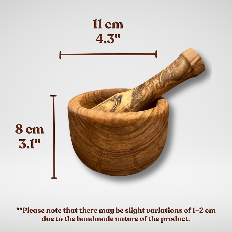 K&ouml;nnte beinhalten: Ein h&ouml;lzernes M&ouml;rser- und St&ouml;&szlig;el-Set. Der M&ouml;rser ist 8 cm hoch und 11 cm breit. Das Set besteht aus hellbraunem Holz mit einem nat&uuml;rlichen Maserungsmuster. Der St&ouml;&szlig;el liegt im M&ouml;rser.