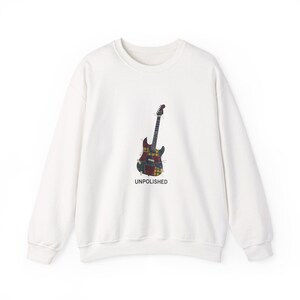 Può includere: Una felpa bianca con una grafica di chitarra colorata e la scritta "UNPOLISHED" stampata sotto. Il design della chitarra incorpora vari motivi e colori, tra cui rosso, verde e giallo.