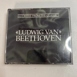 Può includere: Un cofanetto per CD nero con la scritta "FAVORITES FROM THE CLASSICS" in alto. Sotto, il testo "LUDWIG VAN BEETHOVEN" è visualizzato in bianco. Il cofanetto è racchiuso in plastica trasparente.