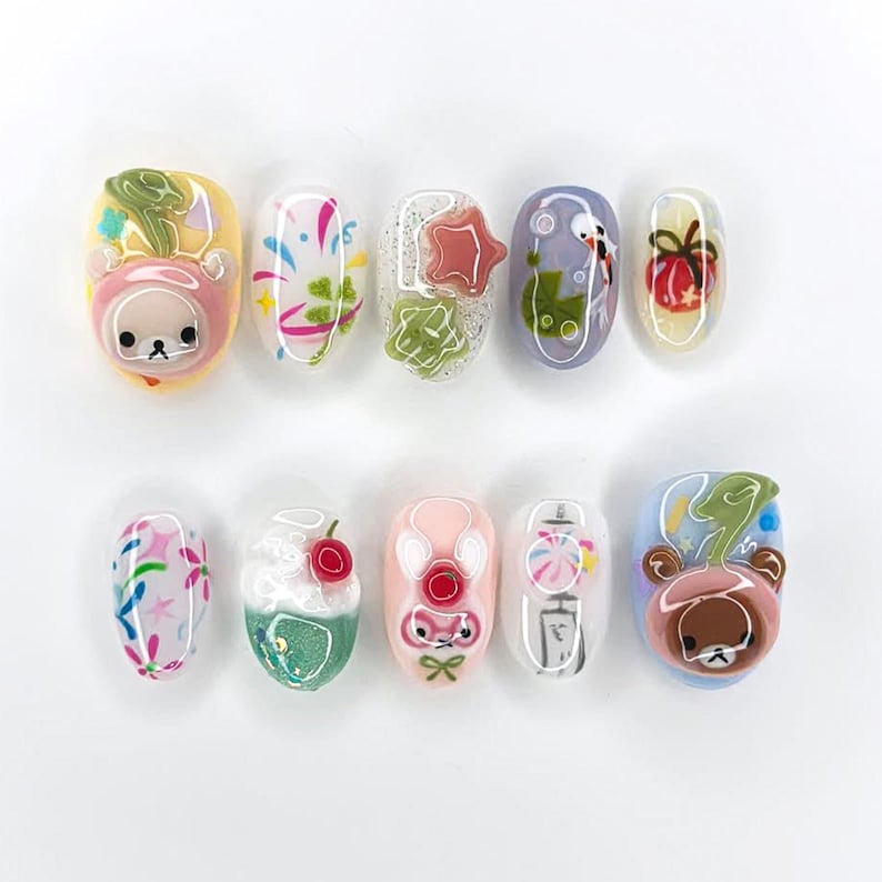 Peut inclure: Dix faux ongles d&eacute;cor&eacute;s de motifs vari&eacute;s. Les ongles pr&eacute;sentent des personnages de dessins anim&eacute;s, des feux d'artifice et d'autres &eacute;l&eacute;ments d&eacute;coratifs dans une vari&eacute;t&eacute; de couleurs, dont le rose, le jaune et le bleu.