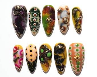 Uñas postizas texturizadas con espirales, uñas en tonos dorados y terrosos, diseño de uñas con puntos abstractos, uñas con un toque retro y uñas artísticas 3D únicas.