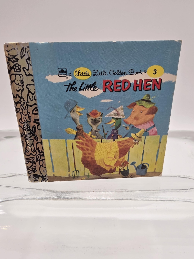 May include: A vintage Little Golden Book titled "The Little Red Hen." The cover features a blue background with illustrations of a red hen and other farm animals. The book's spine has a patterned design.
