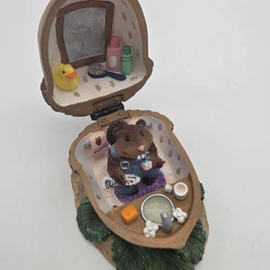 May include: A white ceramic mug with a black handle and the text "But First, Coffee" in a bold, black font. The mug is set against a neutral background, highlighting its simple design.