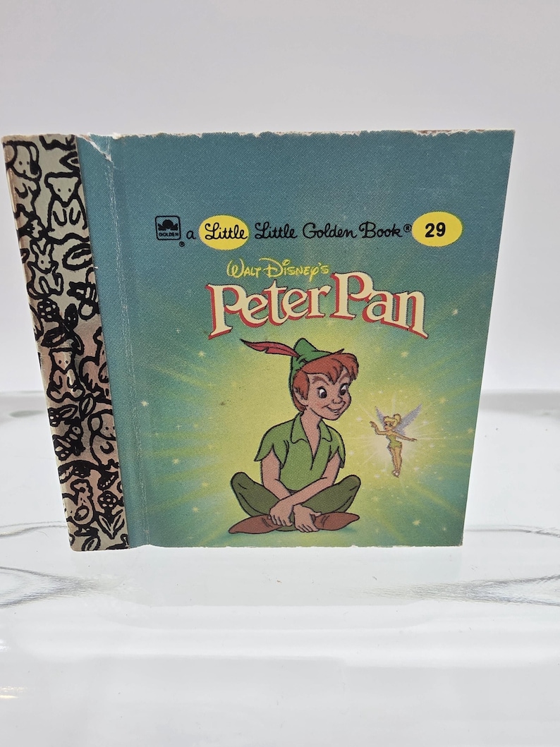 May include: A vintage "Little Golden Book" titled "Peter Pan" by Walt Disney. The cover features an illustration of Peter Pan and Tinkerbell on a teal background. The spine has a black and white pattern.