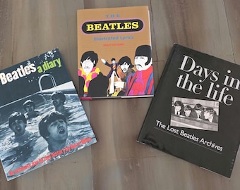 May include: Three books about The Beatles. One book is titled "The Beatles Illustrated Lyrics" with a tan cover and a colorful illustration. Another book is titled "The Beatles' a diary" with a blue cover. The third book is titled "Days in the life" with a black cover.
