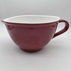 May include: A burgundy ceramic mixing bowl with a white interior. The bowl has a pouring spout and a handle. This kitchenware item is ideal for baking and cooking.