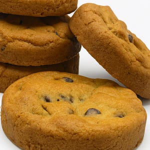 May include: A stack of golden-brown chocolate chip cookies with dark chocolate chips. The cookies are round and have a slightly textured surface, with some chips visible on top.
