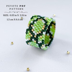 Wide peyote stitch beaded ring with a green and gold snake-skin inspired pattern. Made with shades of lime, dark green, white, and metallic gold beads. Displayed on a light background with scattered gold seed beads.
