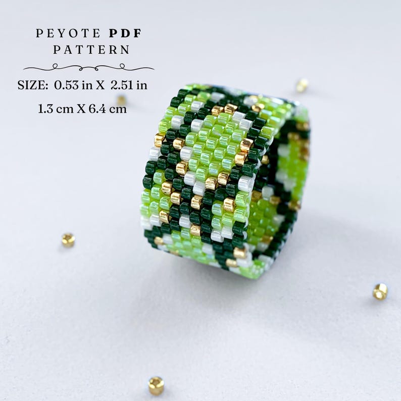 Wide peyote stitch beaded ring with a green and gold snake-skin inspired pattern. Made with shades of lime, dark green, white, and metallic gold beads. Displayed on a light background with scattered gold seed beads.