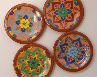 May include: Four small terracotta plates with hand-painted designs. Each plate features a different floral pattern in shades of blue, green, yellow, and orange.