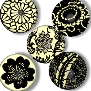 May include: Five round, cream-colored coasters with black floral designs. The designs include a large flower, a smaller flower, a stylized flower, a leaf, and a floral pattern.