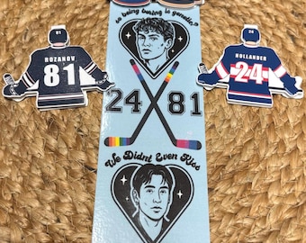 May include: A light blue bookmark with hockey-themed graphics. It features jersey illustrations with the numbers 24 and 81, along with the names "Hollander" and "Rozanov." The text "so being boring is genetic?" and "We Didn't Even Kiss" are also present.