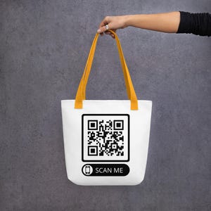 Könnte beinhalten: Weiße Einkaufstasche mit gelben Henkeln, einem schwarz-weißen QR-Code und dem Text "SCAN ME".