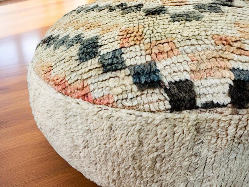 Pu&ograve; includere: Un pouf rotondo e strutturato con base color crema e parte superiore a fantasia. La parte superiore presenta un design geometrico nei toni del crema, rosa, blu e nero. Il pouf &egrave; realizzato in un materiale morbido e tessuto, ideale per un soggiorno o una camera da letto.