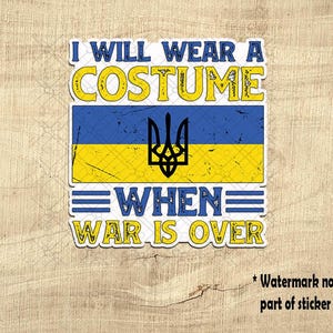 May include: A sticker with the text "I WILL WEAR A COSTUME WHEN WAR IS OVER" in blue and yellow. The design includes the Ukrainian flag and a coat of arms. The sticker has a distressed, vintage look.