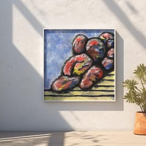 Puede incluir: Pintura abstracta enmarcada en blanco. La obra presenta un grupo de formas rojas, amarillas y azules sobre un fondo azul. La pintura está colgada en una pared blanca, con una planta en maceta en primer plano.