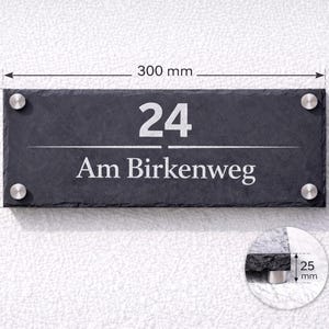 Op de afbeelding: Een rechthoekig huisnummerbord van donkergrijze leisteen met het nummer 24 en de tekst Am Birkenweg in het wit. Het bord is bevestigd met vier zilverkleurige metalen afstandhouders, meet 300 mm bij 150 mm, met een dikte van 25 mm in een inzet.