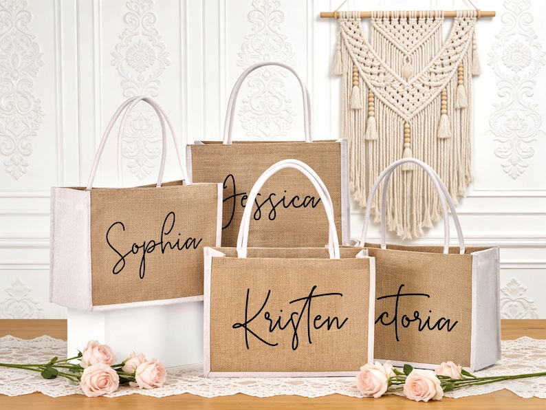 May include: Five burlap tote bags with white handles and trim. Each bag has a different name in black script: Sophia, Jessica, Kristen, and Victoria. The bags are arranged on a table with pink roses.