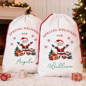 May include: Two white Christmas gift sacks with red drawstrings. Each sack features a Santa Claus graphic, the text "SPECIAL DELIVERY FOR", snowflakes, and a name. A Christmas tree and fireplace are in the background.