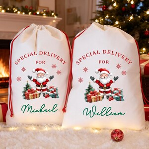 May include: Two white Christmas gift sacks with red drawstrings. Each sack features a Santa Claus graphic, the words "Special Delivery For", snowflakes, and a name. One says "Michael" and the other says "William".