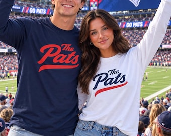 May include: A navy blue long-sleeve shirt with red text reading The Pats and a white long-sleeve shirt with navy blue text reading The Pats. Both shirts feature a crew neckline and are worn with light blue denim jeans and denim shorts.