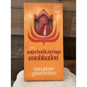 May include: An orange box with a red water bottle/syringe combination. The box has the word "COMFY" and the text "water bottle/syringe combination" in brown. The box also has the text "two-year guarantee" in white.