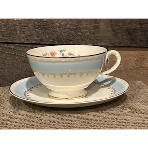 Peut inclure: Un service à thé vintage composé d'une tasse et d'une soucoupe. La tasse présente une bande bleu clair et des motifs floraux, avec un bord doré. La soucoupe reprend le design de la tasse, pour une esthétique élégante. Un classique.
