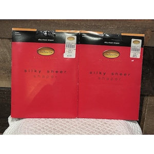 May include: Two red boxes of Talbots silky sheer shapers. The boxes have black and gold accents and the words "silky sheer shaper" printed on the front. The boxes are on a white surface.
