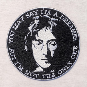 Puede incluir: Un parche bordado circular en blanco y negro con un retrato de un hombre con gafas. El texto alrededor de la imagen dice: "BUT YOU MAY SAY I'M A DREAMER, BUT I'M NOT THE ONLY ONE."