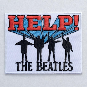 May include: Embroidered patch featuring the word "HELP!" in red block letters above a blue and white design. Below the text are black silhouettes of four figures with their arms raised. The text "THE BEATLES" is below the figures.