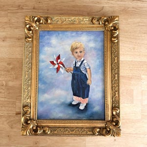 May include: An oil painting in a decorative gold frame featuring a young child with blonde hair wearing dark blue denim overalls over a white shirt. The child holds a red and white pinwheel against a soft blue and white cloudy background.