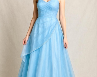 May include: A light blue formal gown with a sweetheart neckline and spaghetti straps. The dress features a layered skirt with a sparkling, sheer overlay. The model is wearing the dress in a studio setting.