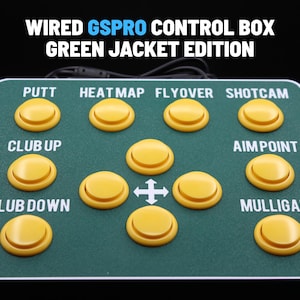 May include: A green control box with yellow buttons labelled "PUTT", "HEATMAP", "FLYOVER", "SHOTCAM", "CLUB UP", "CLUB DOWN", "AIMPOINT", and "MULLIGAN". The text "WIRED GSPRO CONTROL BOX GREEN JACKET EDITION" is at the top.