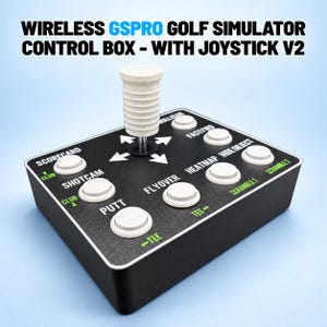 May include: A black wireless GSPRO golf simulator control box with a white joystick V2. The device features multiple white circular buttons labelled with functions including Scorecard, Shotcam, Putt, Flyover, Heatmap, Hide Object, and Scramble.