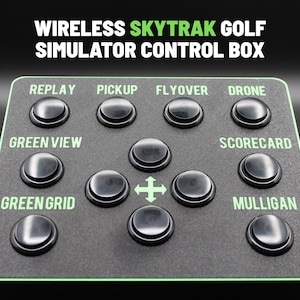 Puede incluir: Una caja de control negra para un simulador de golf SkyTrak inalámbrico. La caja tiene varios botones etiquetados como "Replay", "Pickup", "Flyover", "Drone", "Green View", "Scorecard", "Green Grid" y "Mulligan". El texto "Wireless SkyTrak Golf Simulator Control Box" está en la parte superior.