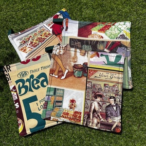 May include: Four vintage-style pot holders with different designs. One features a woman in a dress and a bucket, another has a grocery store scene with the text "FOR SALE BY YOUR GROCER", another has a woman in a dress and a grocery store scene, and the last one has a grocery store scene with the text "IGA TABLE TREAT Brea 5 LO".