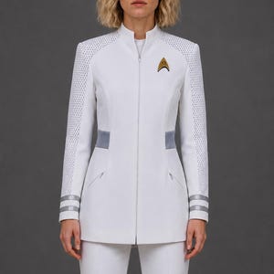 Op de afbeelding: Een wit jack met lange mouwen, een hoge kraag en een ritssluiting over de gehele voorzijde. De schouders en mouwen hebben een gestructureerd wit mesh-patroon. Een goudkleurig Starfleet-delta-insigne is op de linkerborst gespeld. De taille heeft grijze zijpanelen en de manchetten zijn voorzien van twee horizontale zilveren strepen.