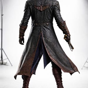 May include: A black leather hooded coat with brown detailing, worn with matching boots and gloves. The coat has a long, split back and a belt at the waist. A prop weapon is held in the right hand. Suitable for cosplay or theatrical performances.