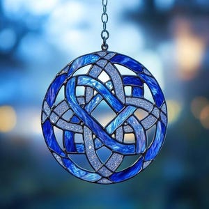 May include: A round, stained glass ornament with a Celtic knot design. The ornament features shades of blue and silver, with a chain for hanging. The intricate pattern is visible against a blurred blue background.