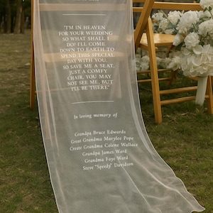 May include: A sheer white wedding chair veil with printed text. The text includes a poem and a list of names, set against a backdrop of wooden chairs and greenery. The veil is draped over a chair.