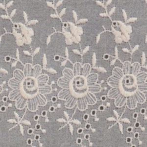 May include: White cotton fabric with a delicate embroidered floral design. The embroidery features small flowers and leaves with a scalloped edge.