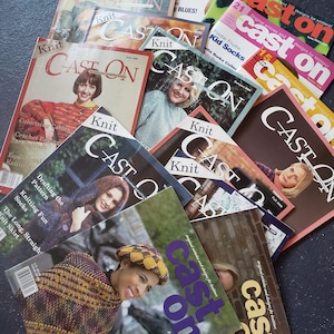 Puede incluir: Una pila de revistas coloridas con el título "Cast On" en la portada. Las revistas son sobre tejido y presentan varios proyectos y patrones de tejido.