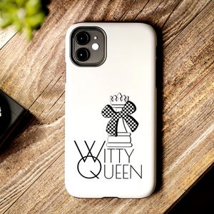 May include: White phone case featuring a black and white chess queen design and the words "Witty Queen". The case is on a wooden surface with a plant and a camera in the background.